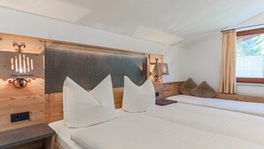 A modern bedroom with a wooden headboard, two beds, a bedside table, and a window with curtains. - Apartment Brixen Near Ski Lift (Brixen im Thale)