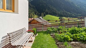 A house with a wooden bench outside, a garden with various plants, and a mountain view in the background. - Apartment in Kappl Near Ski Lift (Kappl)