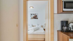A narrow hallway leading to a bedroom with a bed, a painting, and a wooden floor. - Apartment in Kappl Near Ski Lift (Kappl)