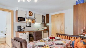 A compact kitchen with modern appliances, a dining area with a patterned tablecloth, and a cozy seating area with striped cushions. - Apartment in Kappl Near Ski Lift (Kappl)