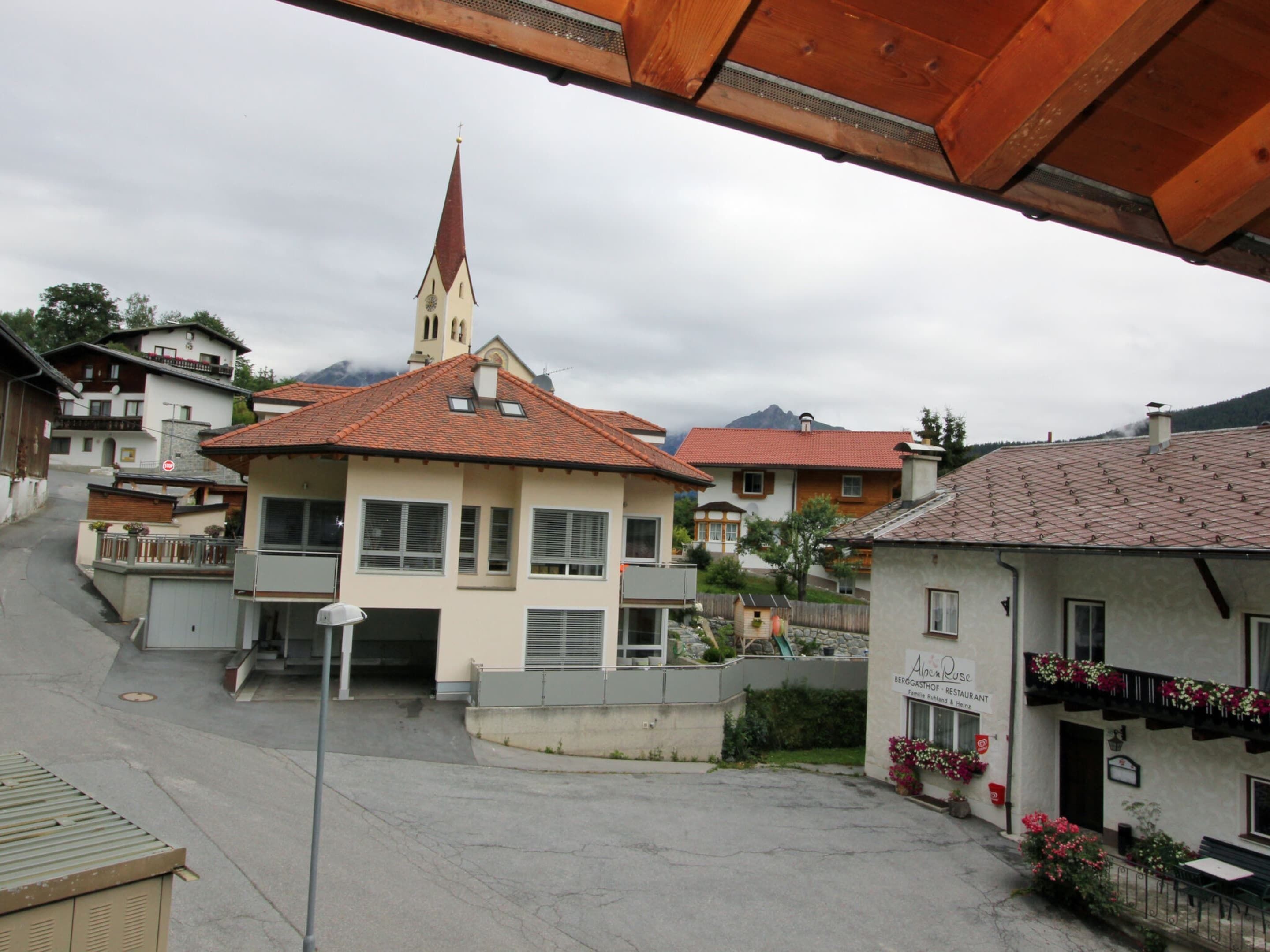 Ein Gebäude mit rotem Ziegeldach und einem Kirchturm im Hintergrund.