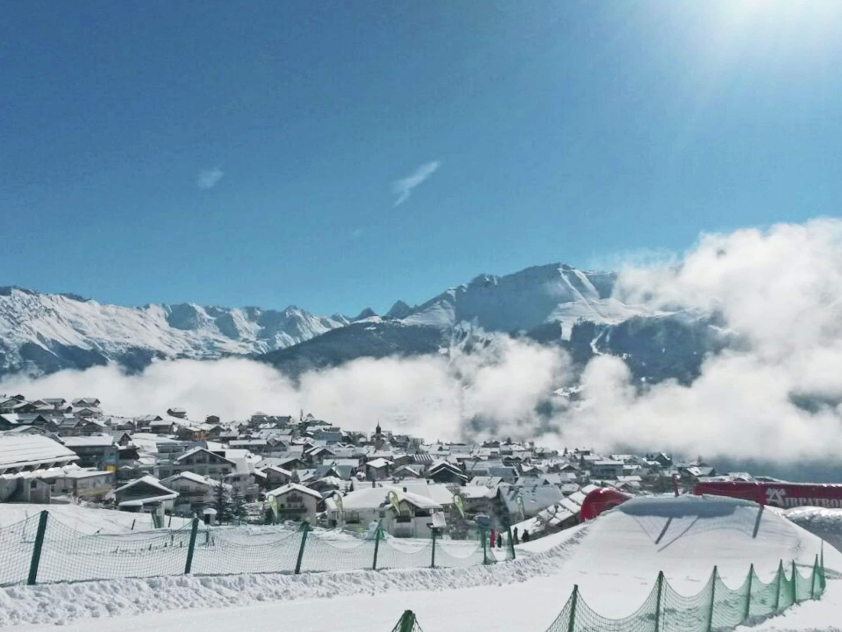 Un village enneigé avec des maisons et une piste de ski.