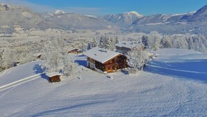 Un village de montagne enneigé, avec des chalets en bois et un ciel d’un bleu limpide.