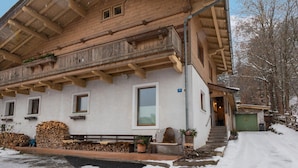 A wooden chalet with a balcony, a bench, and a pile of firewood outside. - Modern Apartment in Kitzbuhel Near Ski Area (Kitzbuhel)