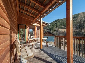 Une cabane en bois dotée d’un porche abrité et offrant une vue sur un lac et des montagnes.