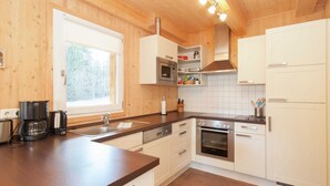 Moderni keittiö, jossa on puiset kaapit, sisäänrakennettu uuni, mikroaaltouuni ja kahvinkeitin.