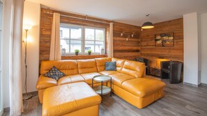 A modern living room with a sectional sofa, a small round table, and a fireplace. - Apartment in Brixen Near Skiwelt Lift (Brixen im Thale)