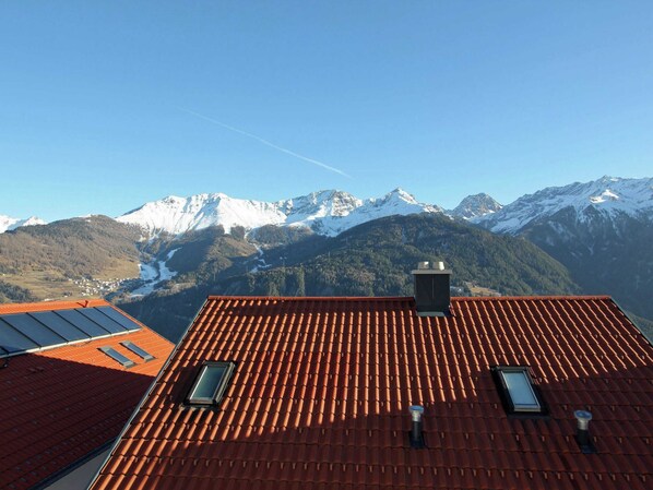 A rooftop with red tiles, two skylights, and a view of snow-capped mountains.