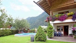 A chalet with a swimming pool, outdoor seating, and mountain views. - Apartment in Waidring Near Ski Slopes (Waidring)