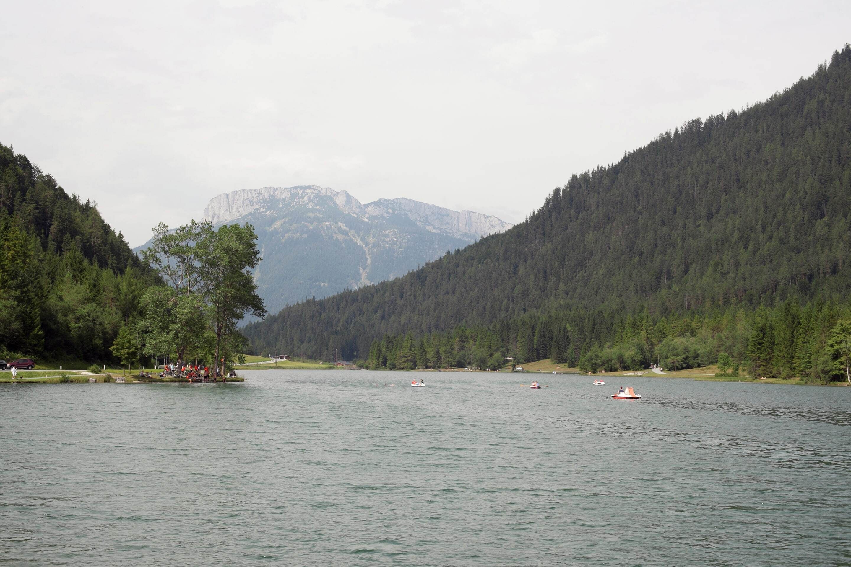 A lake surrounded by forested hills with boats on the water.