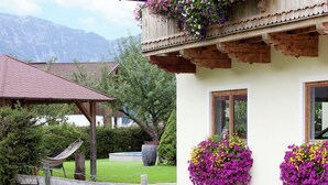 A chalet with a wooden balcony, flower boxes, and a hammock in the yard. - Apartment in Waidring Near Ski Slopes (Waidring)
