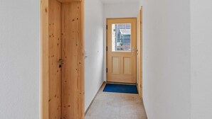 A narrow hallway with wooden doors and a small window at the end. - Apartment in Brixen im Thale in ski Area (Brixen im Thale)