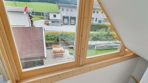 A staircase with a view of a patio area, including a wooden table and chairs, and a building in the background. - Apartment in Brixen im Thale in ski Area (Brixen im Thale)