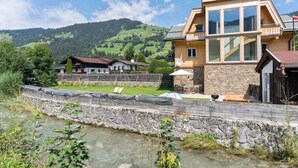 A two-story house with a stone foundation, large windows, and a balcony. - Apartment in Brixen im Thale in ski Area (Brixen im Thale)
