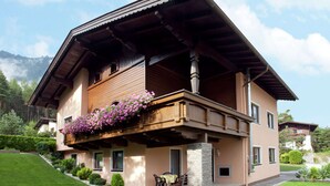 A two-story house with a balcony, a stone pillar, and a well-maintained lawn.
