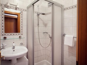 Une salle de bain moderne avec une douche à parois de verre, un lavabo blanc et un miroir orné de carreaux décoratifs.