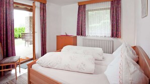 A bedroom with a bed, a wooden desk, and a chair.