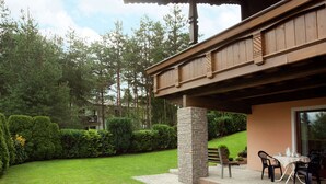 A covered patio area with a stone pillar, a wooden bench, and a table with chairs.