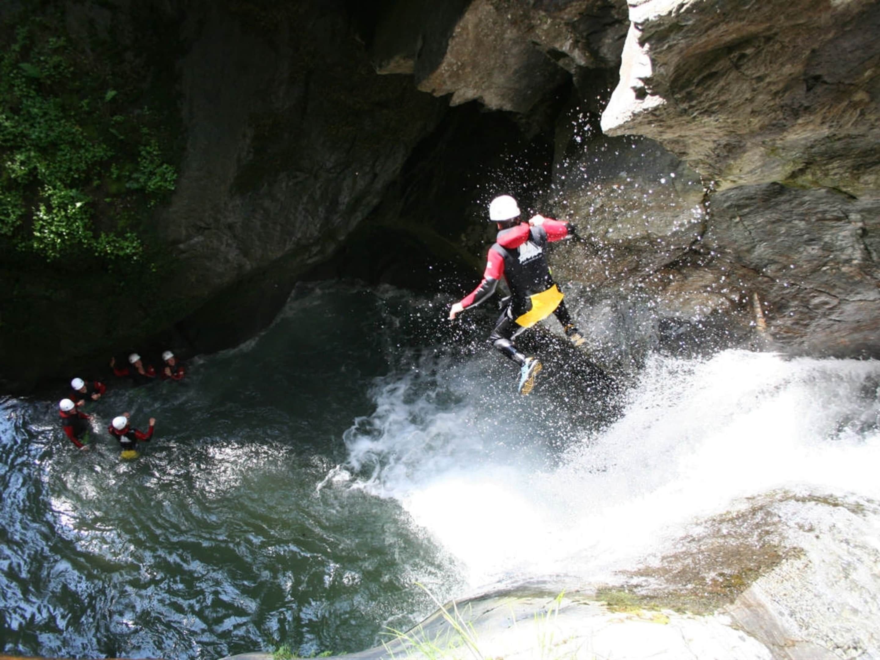 A white water rafting activity with participants in red and black gear.
