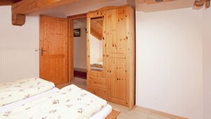 Ein Schlafzimmer mit zwei Betten, einem Holzschrank und einer Tür zu einem anderen Raum.