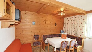 A wooden cabin interior with a dining table, chairs, a sofa, a television, and a ceiling fan. - Apartment in Kappl Near Ski Lift (Kappl)