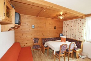 A wooden cabin interior with a dining table, chairs, a sofa, a television, and a ceiling fan. - Apartment in Kappl Near Ski Lift (Kappl)