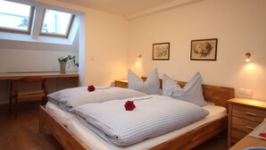A bedroom with a wooden bed, checkered bedding, a desk, and two windows. - Spacious Apartment in Kitzbuhel near Ski Lift (Kitzbuhel)