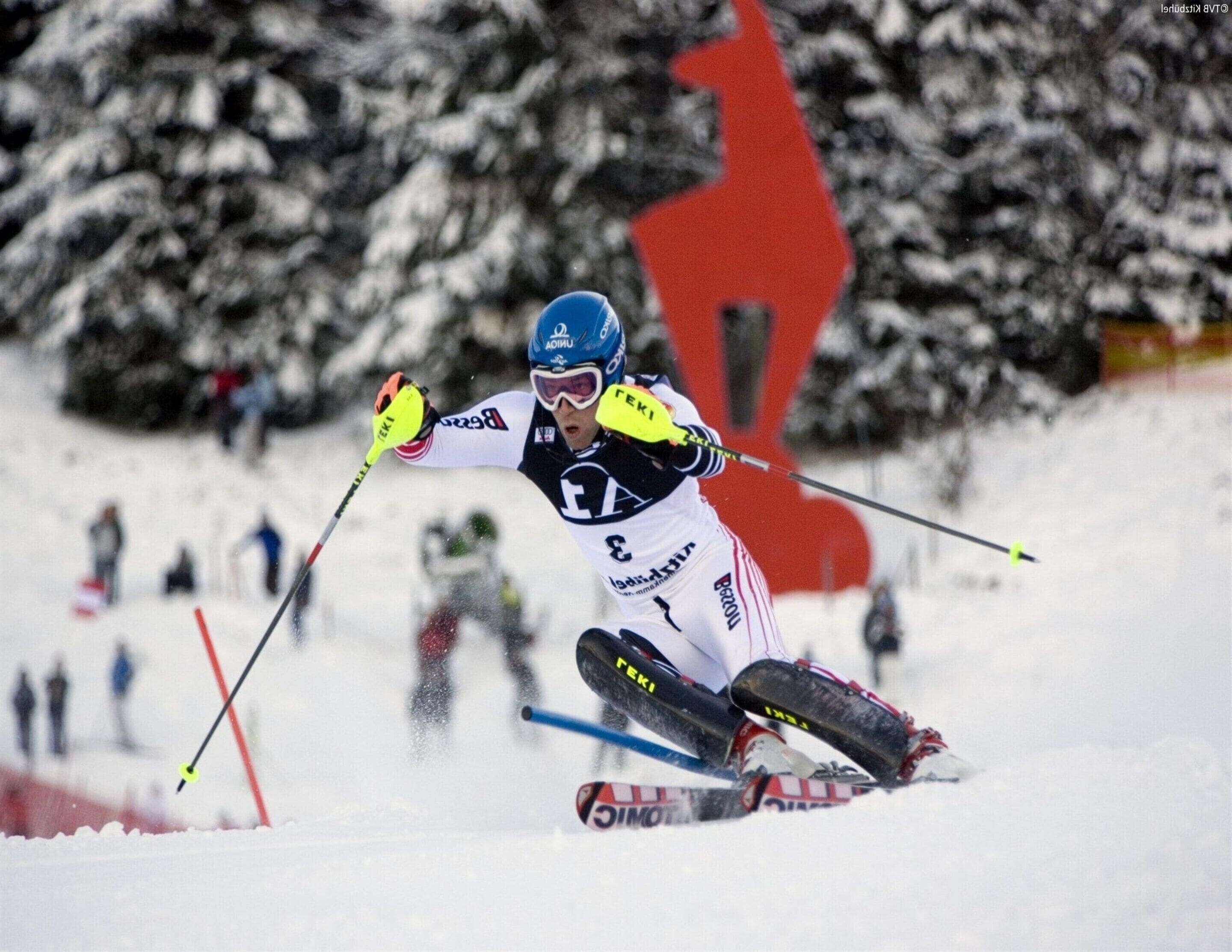 A skier in motion on a snowy slope with a red flag in the background.
