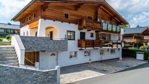 A two-story wooden chalet with a stone staircase and a balcony. - Spacious Apartment in Kitzbuhel near Ski Lift (Kitzbuhel)