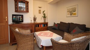 A living room with wicker furniture, a television, a cabinet, and a bookshelf. - Spacious Apartment in Kitzbuhel near Ski Lift (Kitzbuhel)