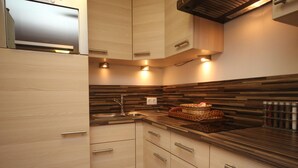 A modern kitchen with wooden cabinets, a stainless steel sink, and a built-in microwave. - Spacious Apartment in Kitzbuhel near Ski Lift (Kitzbuhel)