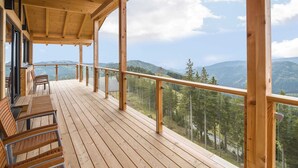 A wooden deck with a glass balustrade overlooking a mountainous landscape. - Chalet in Klippitztorl ski Area With Sauna (Bad Sankt Leonhard im Lavanttal)