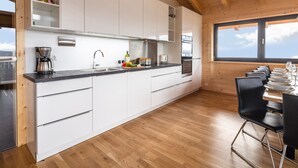 A modern kitchen with white cabinets, stainless steel appliances, and a wooden ceiling. - Chalet in Klippitztorl ski Area With Sauna (Bad Sankt Leonhard im Lavanttal)