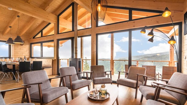 A spacious room with large windows, wooden furniture, and a fireplace. - Chalet in Klippitztorl ski Area With Sauna (Bad Sankt Leonhard im Lavanttal)