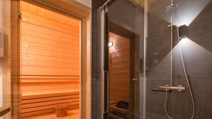 A sauna with wooden benches and a glass door leading to a shower area with dark tiles. - Chalet in Klippitztorl ski Area With Sauna (Bad Sankt Leonhard im Lavanttal)