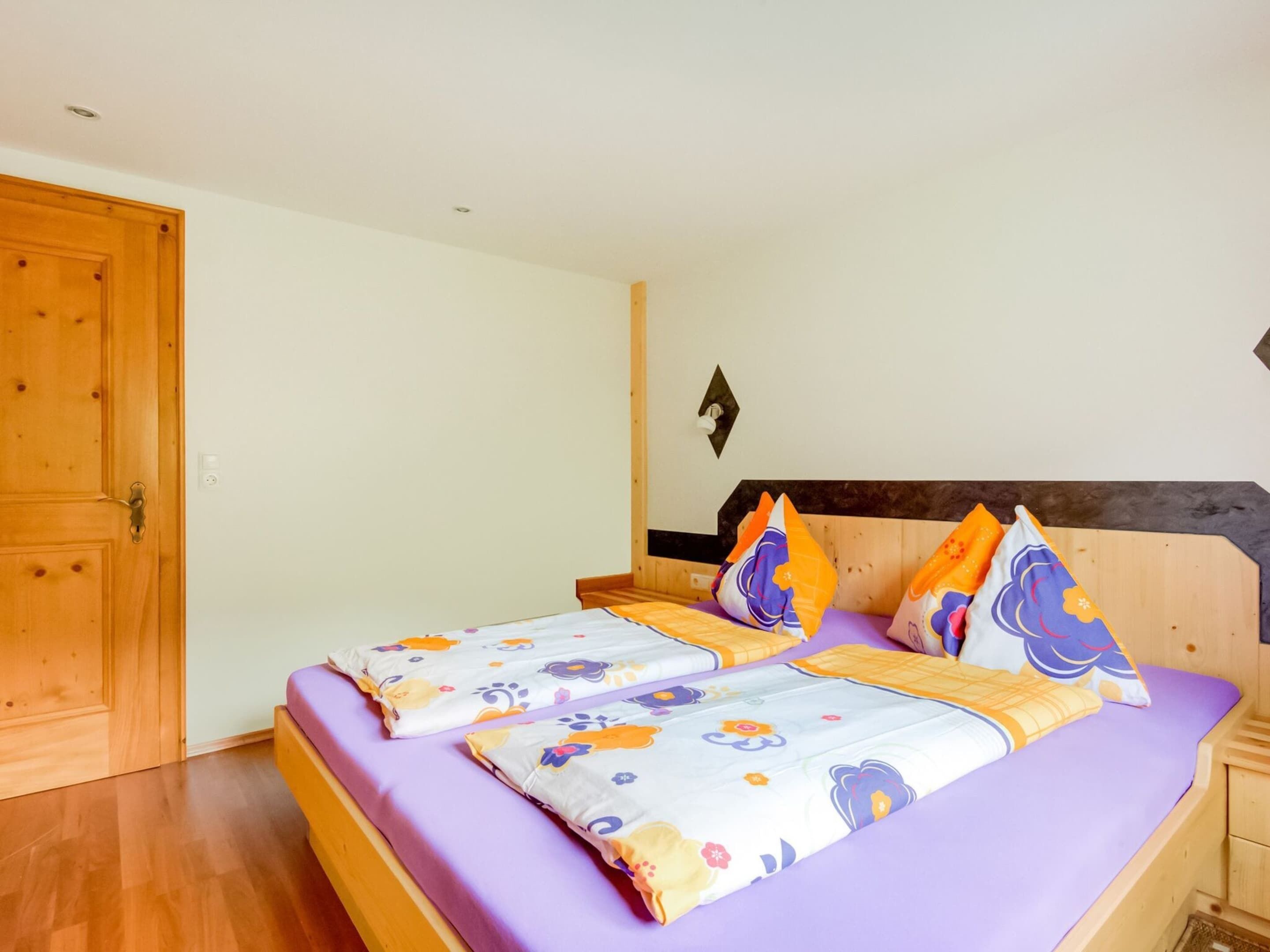 A bedroom with a bed, wooden headboard, and a wooden door.