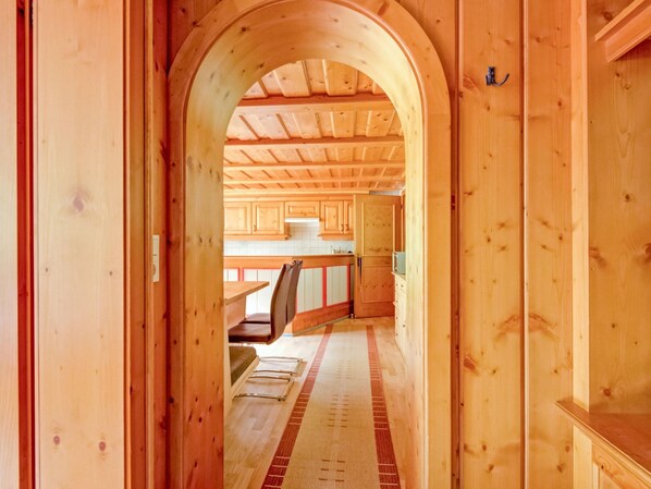 A wooden interior with a hallway leading to a kitchen area, featuring wooden cabinets and a tiled backsplash. - Apartment in Silbertal Near Ski Lift (Silbertal)