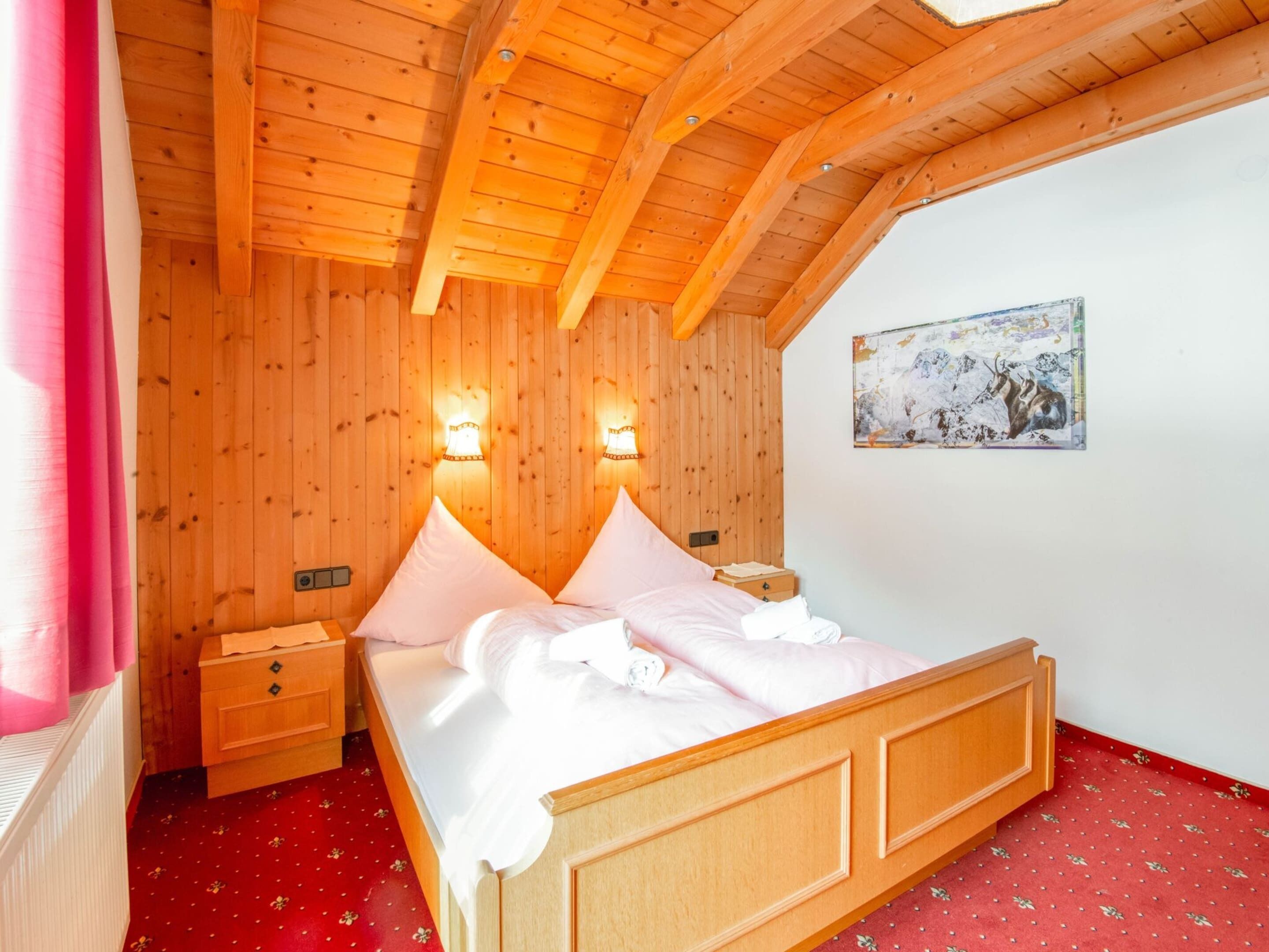 Une chambre à coucher en bois, avec un lit, des tables de chevet et un tableau accroché au mur.