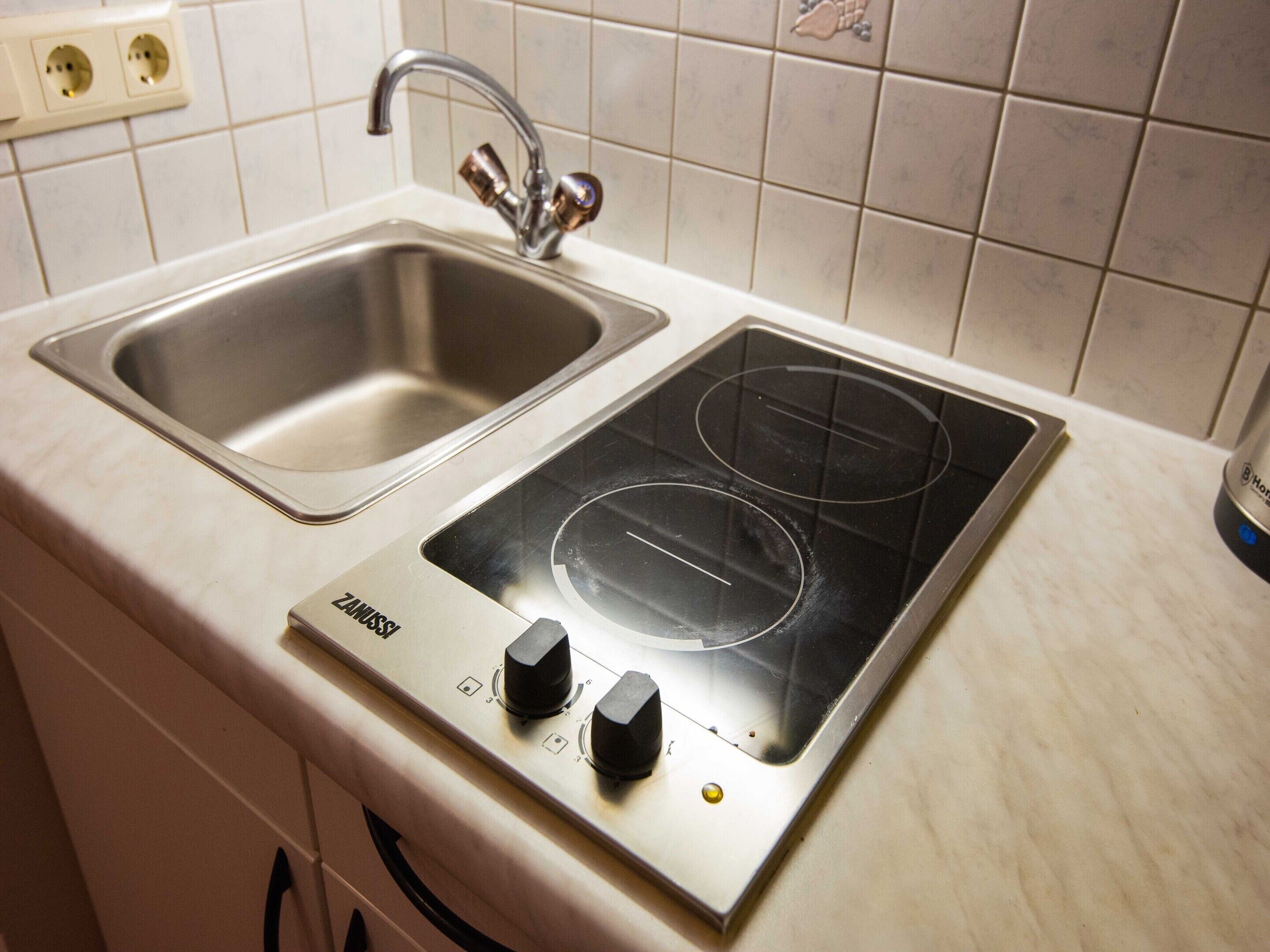 A kitchen with a stainless steel sink and a built-in electric stovetop.