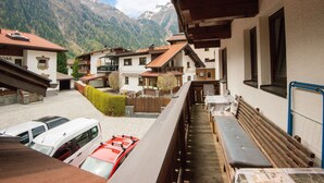 A mountain village with traditional architecture, a covered outdoor seating area, and parked vehicles. - Apartment in Huben Near Ski Slopes (Laengenfeld)
