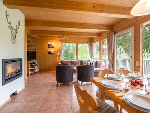 Cozy cabin interior with a fireplace, comfortable seating area, and dining table for two.