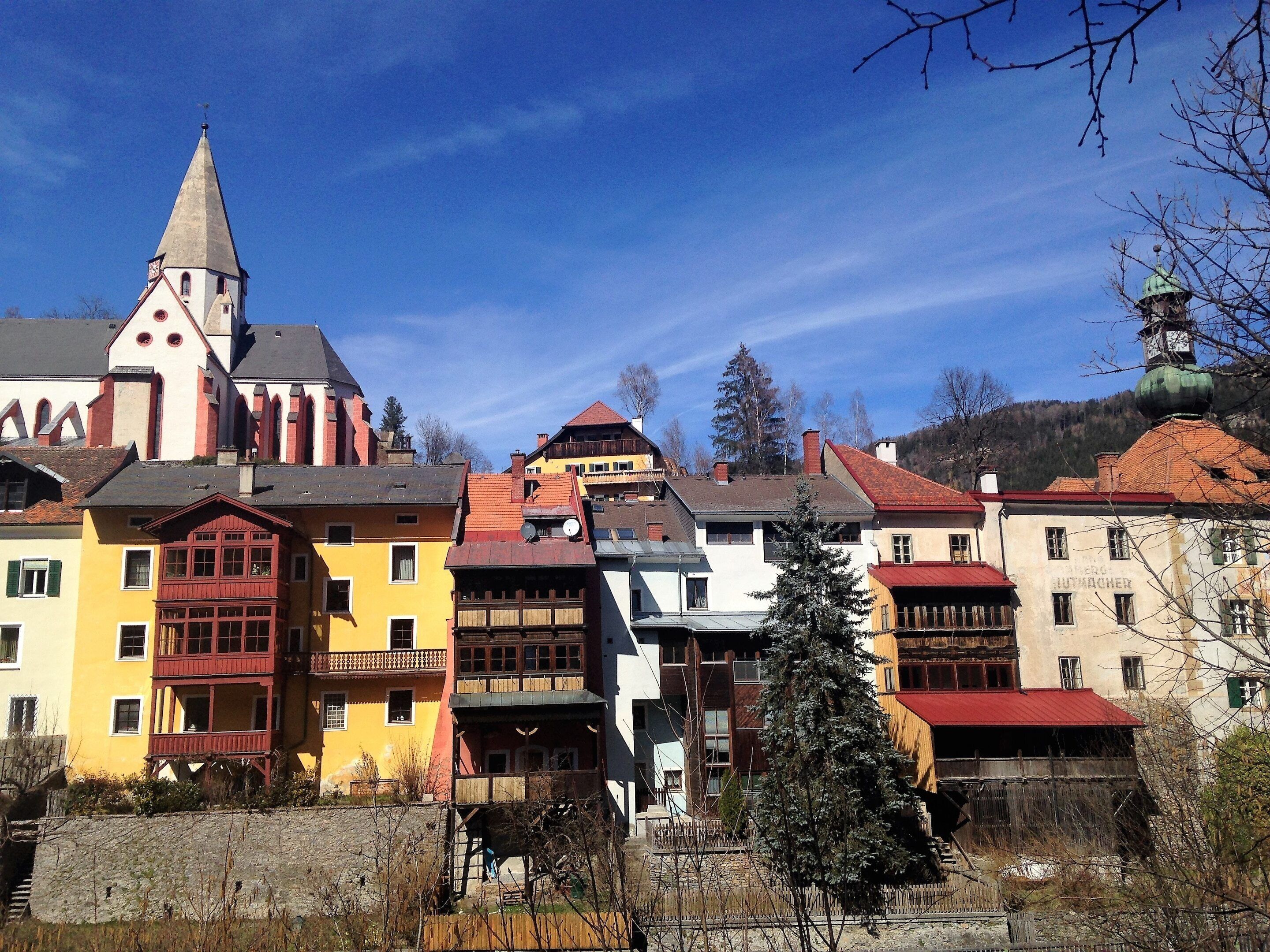 A historic town with colorful buildings, a prominent church tower, and a mix of residential and commercial structures.