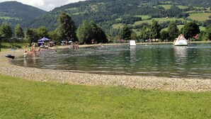 A lakeside area with boats, people, and a grassy shore. - Wooden Chalet in Styria near Kreischberg Ski Area (Sankt Georgen am Kreischberg)