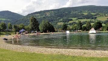 A lakeside area with boats, people, and a grassy shore.