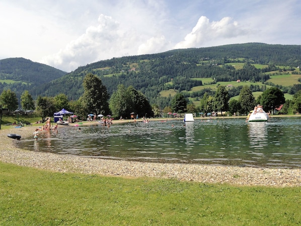 Une zone au bord d’un lac, avec des bateaux, des gens et une rive herbeuse.
