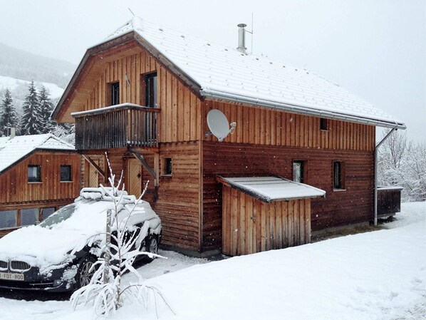 A wooden cabin with a balcony, a covered porch, and a car parked in front. - Wooden Chalet in Styria near Kreischberg Ski Area (Sankt Georgen am Kreischberg)