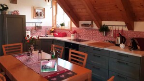 A cozy kitchen with wooden cabinets, a dining table, and a kitchen island. - Apartment in Neuhaus Near Petzen Ski Area (Neuhaus)