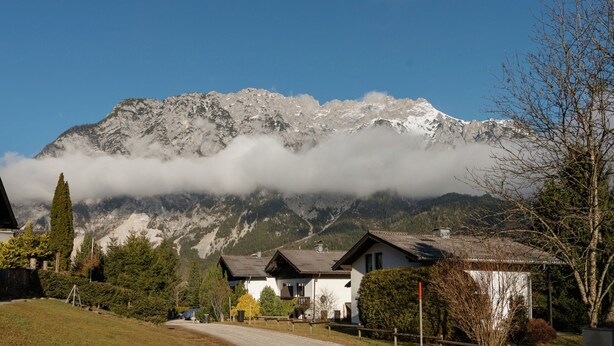 A mountain with a snow-capped peak, a clear sky, and a residential area with houses and a road. - Quaint Holiday in Gröbming near Skiing (Groebming)