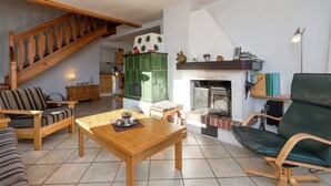 A cozy living room with a wooden staircase, a fireplace, and a green sofa. - Quaint Holiday in Gröbming near Skiing (Groebming)
