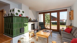 A cozy living room with a fireplace, a sofa, a coffee table, and a view of the outdoors. - Quaint Holiday in Gröbming near Skiing (Groebming)